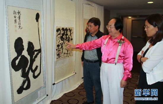   7月10日，中国书法家林中阳（中）在纽约举行的首届中美国际文化艺术品交流展上向参观者介绍自己的作品。