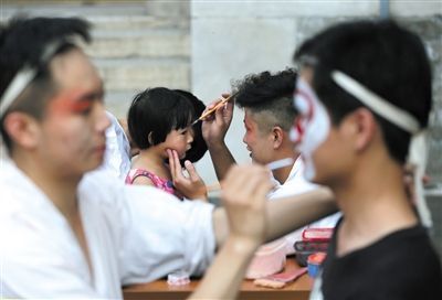 昨日，颐和园内，京剧演员为游客画脸谱。新京报记者 薛珺 摄