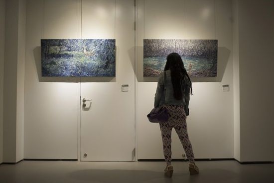 南京，某画展的参观者在欣赏画作。