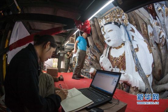 5月7日，文物修复人员在为进行裸露基岩脱盐作业的千手观音主尊造像做详细工作记录。新华社记者 刘潺 摄