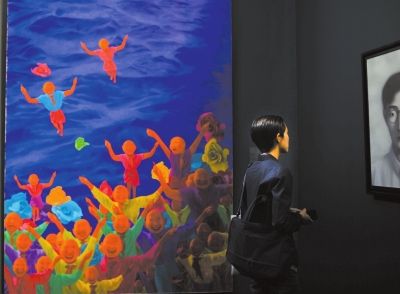 一位参观者在方力钧和张晓刚的画作间驻足欣赏。京华时报记者王苡萱摄