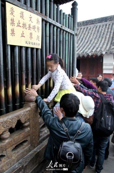 2014年4月5日，湖北武当山景区，部分游客无视景区警示牌子，随意攀爬文物。