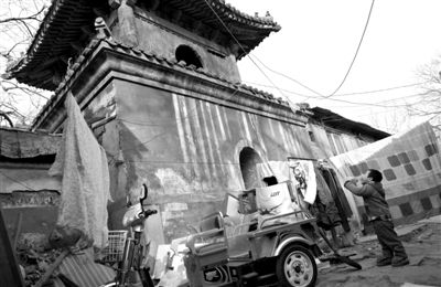 1月25日，一个小男孩在拈花寺前玩耍。钉在寺庙墙上的晾衣架上挂着被子、衣服，旁边还有不少搭建的平房。