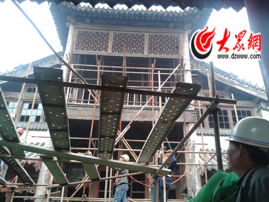 工人们正在搭建脚手架，准备对题壁堂进行修缮。大众网记者 李兆辉 摄