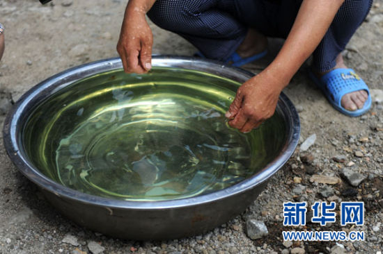 阜新蒙古族自治县那力闪村的一名村民向记者展示刚刚打出的呈绿色的井水（6月24日摄）。新华社记者潘昱龙摄