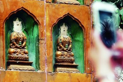 上午，一名游客正在拍摄损坏的佛像摄/记者 付丁