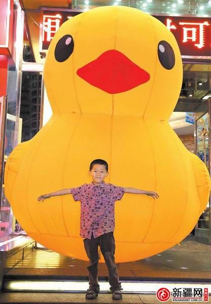 7月10日，一名小朋友与充气大黄鸭合影。（记者刘志龙摄）