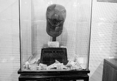 圆明园内，盛放仿真蛇兽首的玻璃箱只有一条通气狭缝，也被游客投入大量钱币 摄/记者 徐超