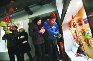 昨天，来自文莱的青年学生在建国门街道社区博物馆内观看风车、京绣等非物质文化遗产展示。本报记者 孙戉摄