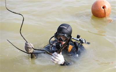 昨日，潜水员从水下返回，带来了沉船上的铁质部件。