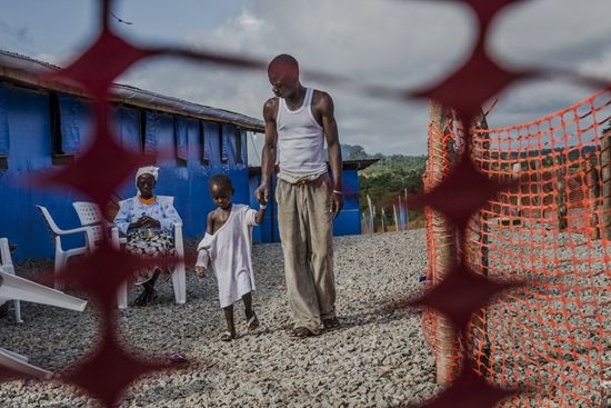 一名叫作George Beyan的埃博拉痊愈者和他埃博拉病毒检验呈阳性的5岁的儿子William一起在Bong County救护中心散步。医务人员告诉他，作为具有免疫能力的痊愈者，他是照料孩子的最佳人选。William在几天后死去。摄于20