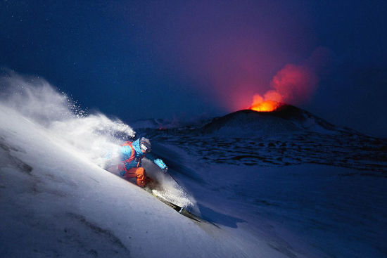 在呼比奈特滑雪而下时，他的背后不远处火山冒出的红色岩浆正在滚滚涌动。