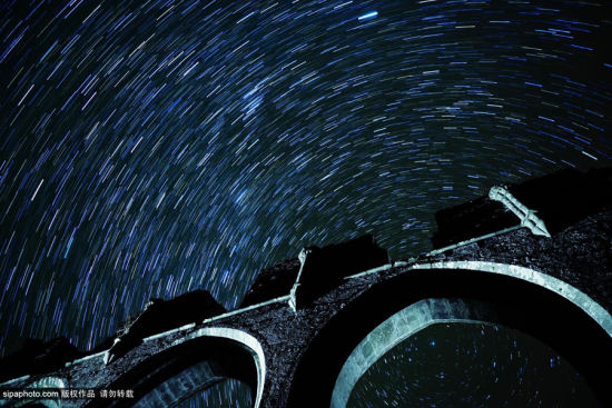 当地时间2014年10月，英国，摄影师摄影师Andrew Whyte镜头下的英国夜景。图为凌晨四点钟布雷肯国家公园兰托尼修道院上空的璀璨星轨。