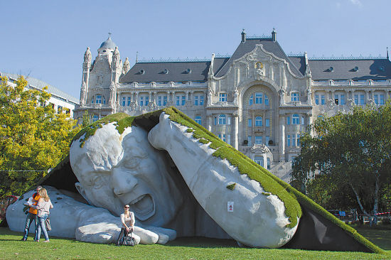 在匈牙利首都布达佩斯，参观者14日和当代艺术展的巨型雕塑《撕裂》合影。