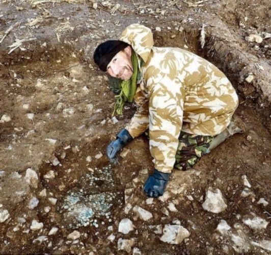 图为宝藏发现者艾格顿先生和还被埋在土里的罗马钱币合影。