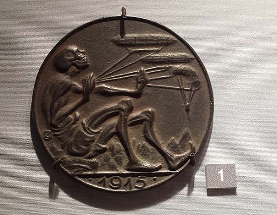 纪念章面，一个骷髅摆弄着齐柏林飞艇（一种硬式飞艇），就像在玩风筝。