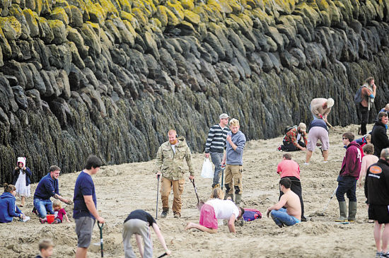 淘金者带着各种装备在沙滩上认真地寻找金条