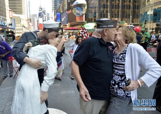 8月14日，在美国纽约时报广场，一名二战老兵与妻子在“胜利之吻”雕塑揭幕仪式上模仿胜利之吻。