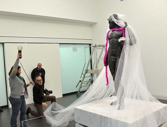 法国摄影师给意大利亚切青铜雕像戴上白色面纱、粉色围巾，甚至穿上豹纹丁字裤拍摄照片。（网页截图）