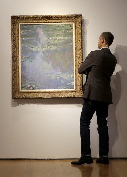 一名男子正在欣赏拍卖行预展的《睡莲》。