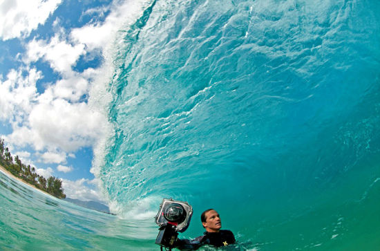 克拉克身穿潜水服，手持巨大的防水相机，正准备拍摄巨浪里的美丽世界