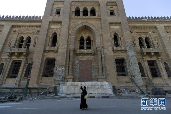 2月9日，在埃及首都开罗，一名当地妇女经过受损的伊斯兰艺术博物馆正门。