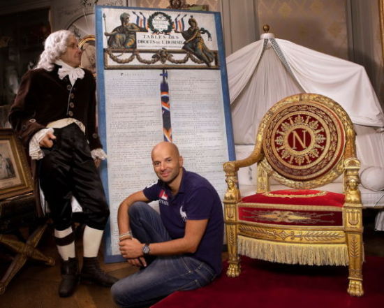 收藏家布鲁诺·勒杜，两旁分别是酷似塔列朗的雕塑模型和拿破仑一世的皇帝御座。这个男人收藏了数量巨大的法国大革命和第一帝国时期的文物，并准备将它们陈列在一座博物馆内。