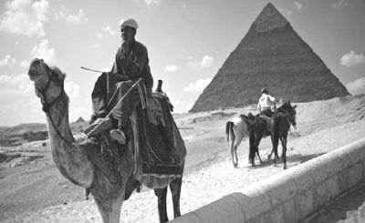 一个埃及人在开罗郊区的吉萨金字塔前等待游客骑骆驼。埃及经济极度依赖外国游客，尤其是在骚乱期间。