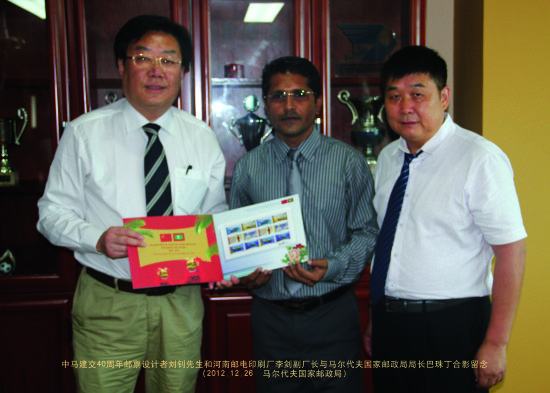 《中马建交40周年》纪念邮票设计者刘钊（左）和河南邮电印刷厂副厂长李剑（右）和马尔代夫邮政总经理巴珠丁合影留念