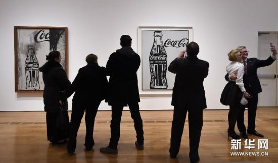 （2）2月26日，在美国亚特兰大高等艺术博物馆举办的“可口可乐弧形瓶”艺术展上，一名参观者观看波普艺术家安迪·沃霍尔的著名系列作品《可口可乐瓶作品》。