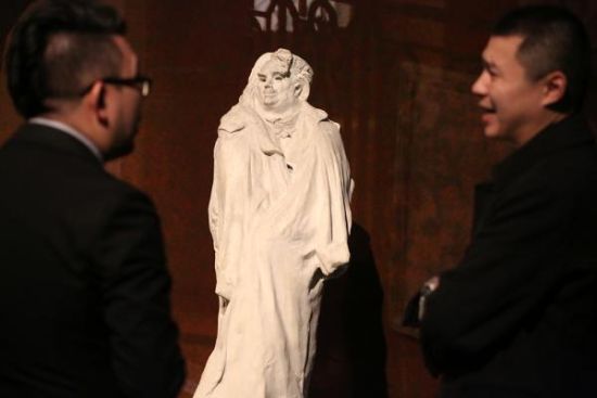 工作人员站在巴尔扎克的雕塑前商讨布展细节