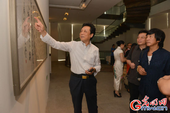 北京书法家协会驻会副主席田伯平（左一）等艺术家在欣赏青年艺术家书画作品