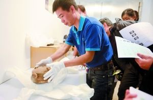 工作人员从封箱中取出香港李郑屋汉墓出土的青黄釉陶鼎。信息时报记者 徐敏 摄