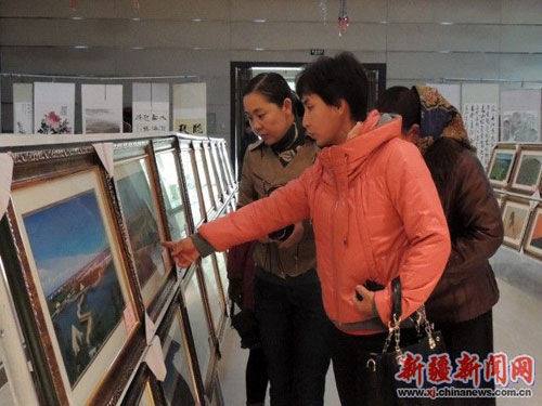 图为博湖县几位城镇居民妇女正在欣赏展出摄影作品 