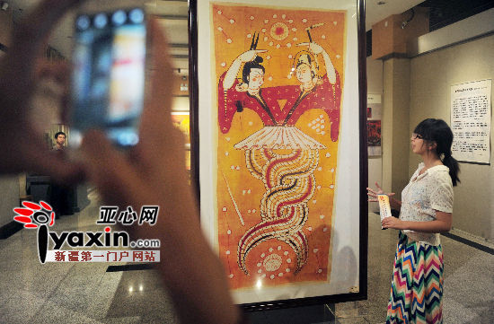 图为8月29日乌鲁木齐市市博物馆一楼展厅，市民在观看新疆出土的古代帛画《伏羲女娲图》。 亚心网记者 张已摄 