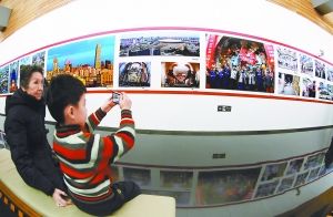 图为一名小观众在美丽北京——“北京精神”群众摄影文化活动优秀作品展上拍摄展览作品。 本报记者 贾同军摄