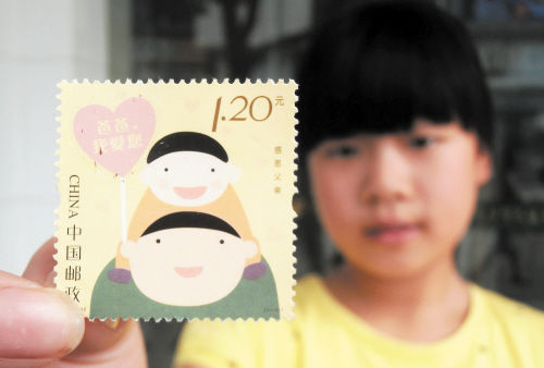 6月13日，一名小朋友在江苏苏州邮政局展示已刮出祝福语的《感恩父亲》特种邮票。新华社发 