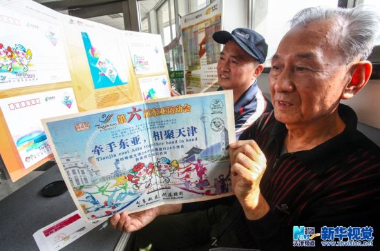 10月6日，两位市民在展示购买的纪念邮品。（李想 摄）