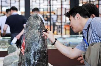 在2014哈尔滨国际珠宝玉石博览会上，一位参会客商在查看一块俄玉原石。记者 王建威 摄
