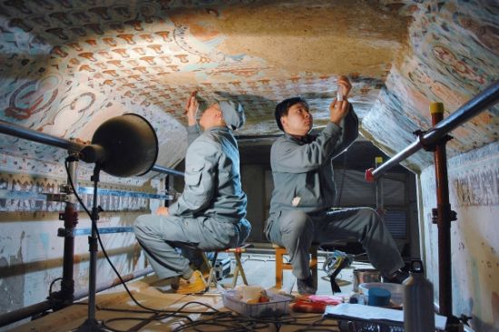 两名工作人员在对莫高窟第85窟壁画进行修复（摄于2005年）