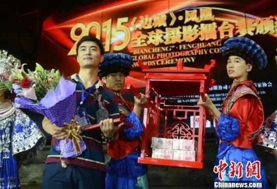 百万摄影巨奖获得者王彬（左一）在100万现金前合影。 杨华峰 摄