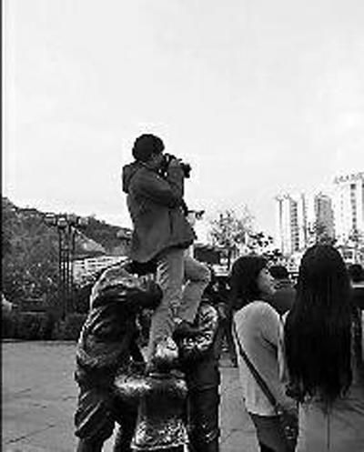 7日下午，延安市延河广场上一女子坐在红军雕塑头上拍照
