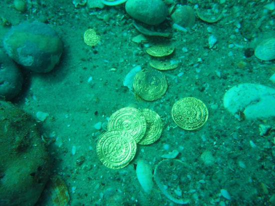 图为考古人员在水下发现的金币。