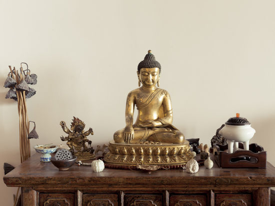 客厅的一个小药柜上摆着不少小物件，最显眼的是一尊铜镏金的佛像