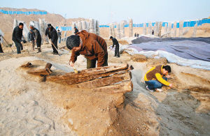 昨日，在渭河桥遗址的厨城门一号桥北端，考古工作人员正在清理发掘出的古船