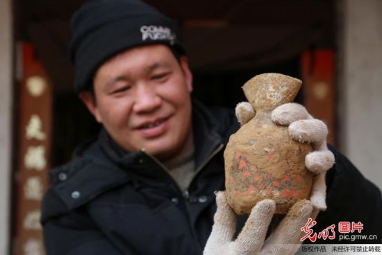 2014年1月5日，在河南省温县，考古工作者张举东在展示出土的一件带有彩绘图案的扁口壶。
