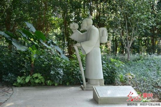 2014年12月8日，广西南宁市，金花茶公园立起了一石雕像作品，一古代穿着的老人玩起了现代摄像机，古代