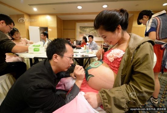 2013年10月27日，重庆市妇幼保健院，重庆孕妈彩绘大赛。30个准爸爸手持画笔，调颜料、画轮廓、上色……专心致志在妻子高高隆起的肚皮上描绘出自己心中的小秘密。摄影 渝友 SipaChina