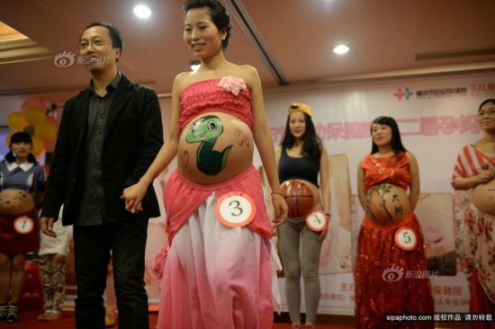 2013年10月27日，重庆市妇幼保健院，重庆孕妈彩绘大赛。丈夫牵手怀孕妻子登台秀恩爱。摄影 渝友 SipaChina