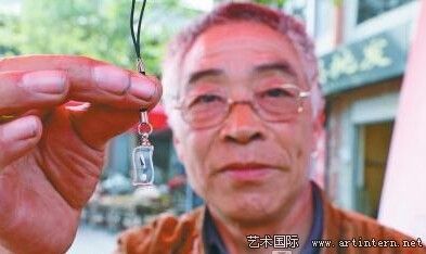 闫交生向记者展示他的米雕作品，齐白石头像被他雕得惟妙惟肖